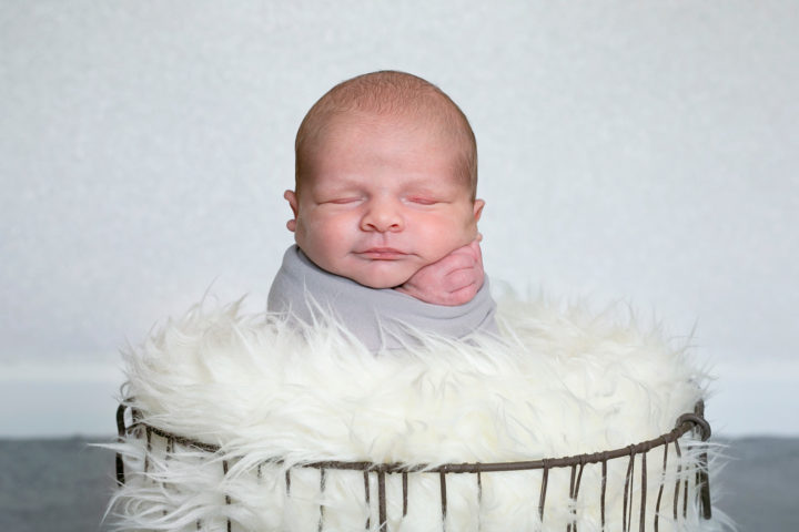 A new baby in a grey wrap in a basket