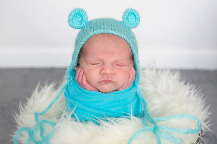 A new baby in a turquoise hat and warp in a basket