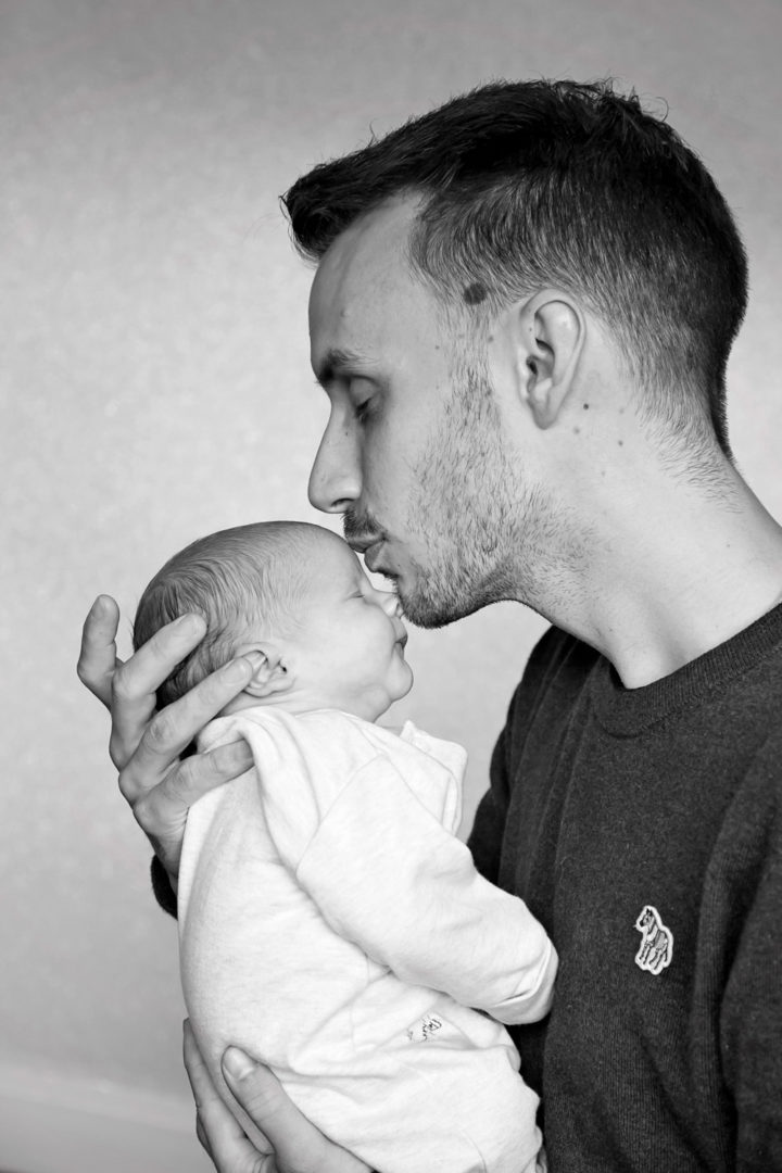 A father kissing his new baby on the forehead